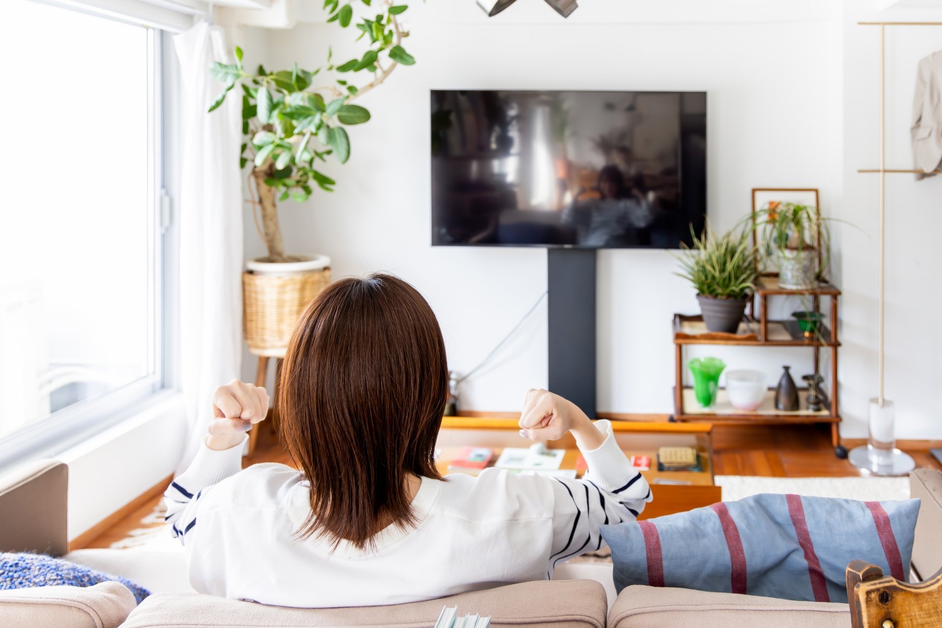テレビの前に座っている女性の後ろ姿